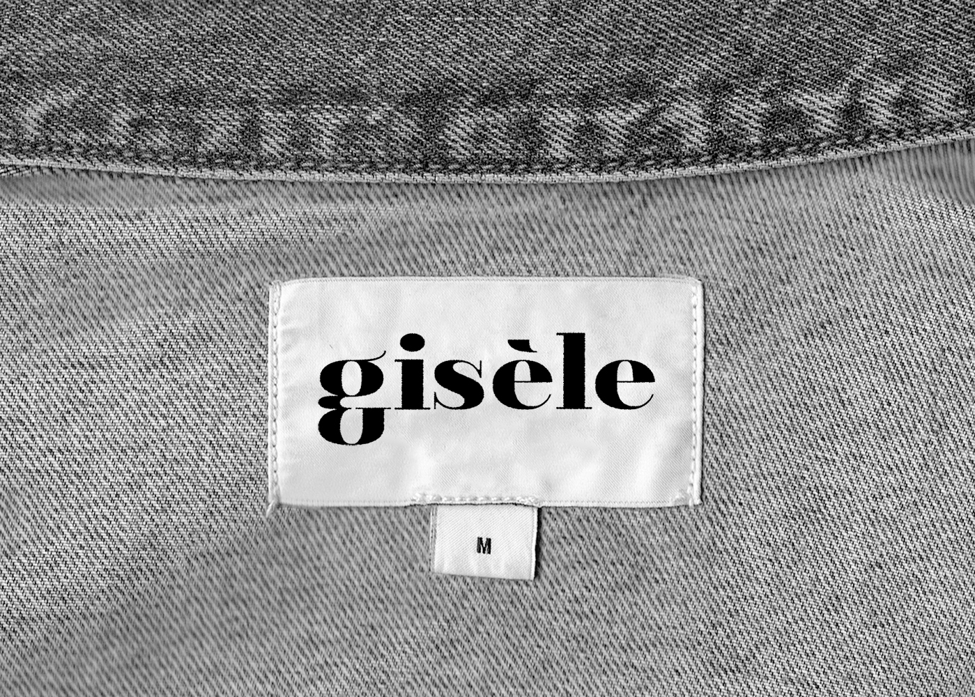 Photographie d'une étiquette brodée de la marque gisèle sur une pièce de vêtement en jeans