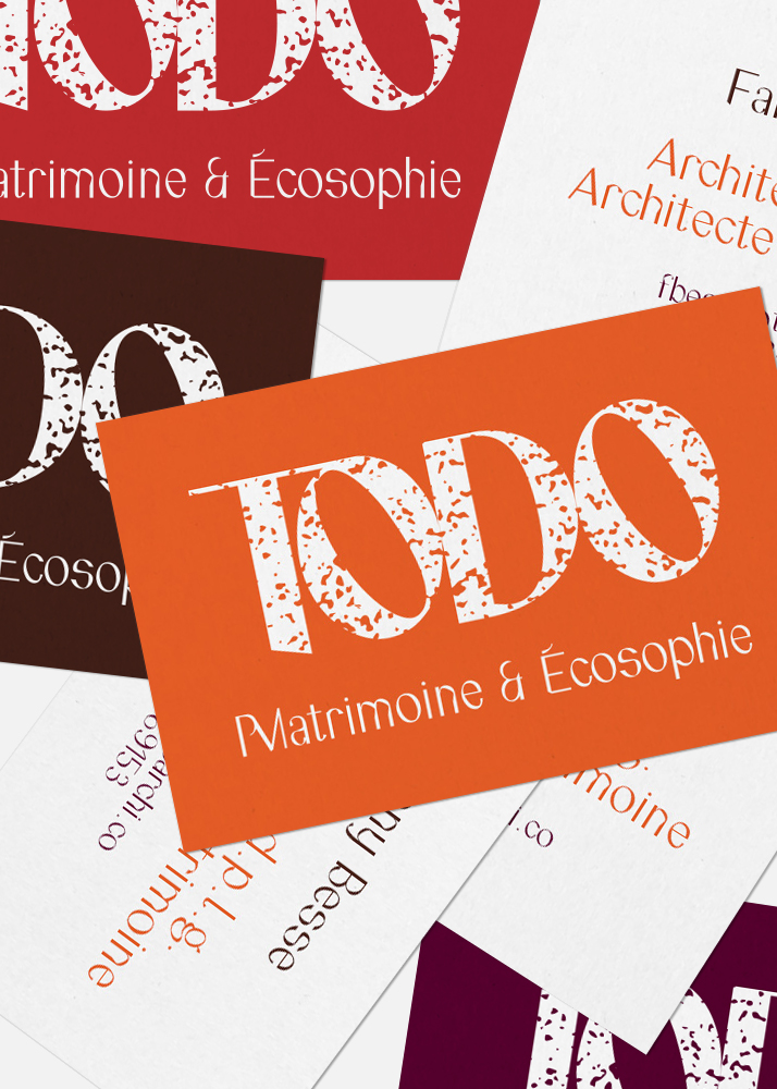 Photographie des cartes de visite réalisées pour l'agence TODO Architecture. Les cartes sont superposées recto/verso présentant les quatre couleurs de la charte graphique.