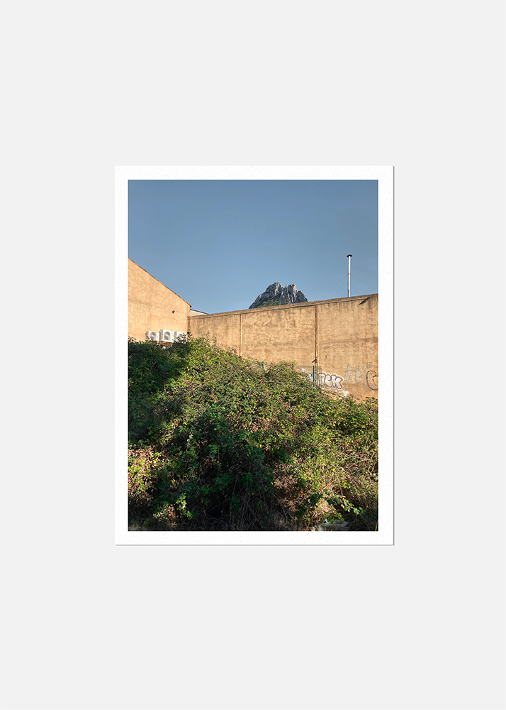 Photographique d'une friche industriel. Une montagne apparait derrière un mur tagué