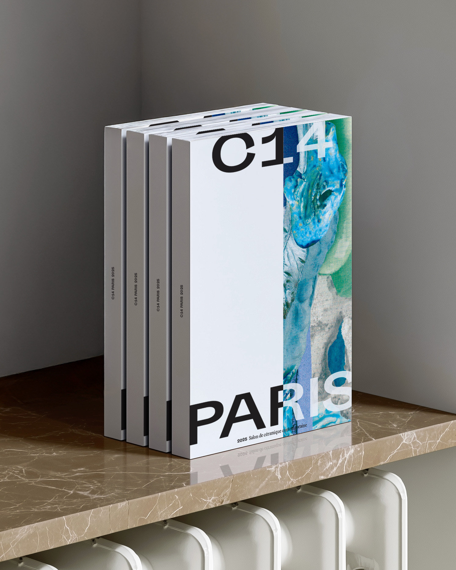 Photographies de quatre catalogues vue de trois quart. On voit la tranche des 4 éditions sur lesquelles il est inscrit